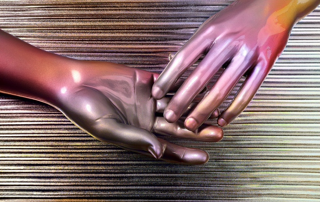Two mannequin hands are posed against a textured, metallic background. One hand is open with the other hand gently placed on top, creating an illusion of touch. The composition is reflective and sleek.